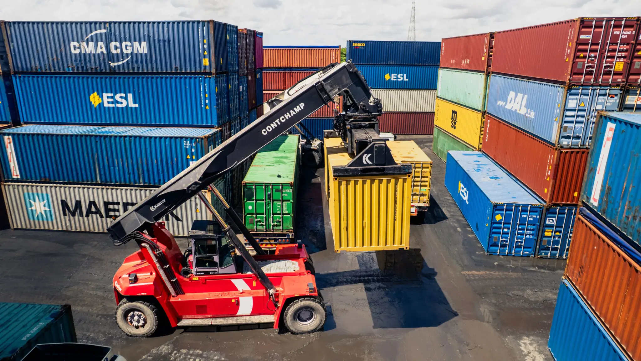 Reach stacker lifting a container in a busy container yard